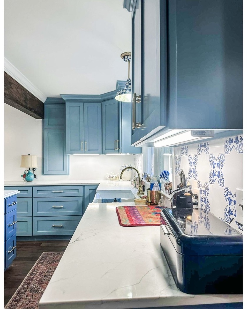 Light blue custom kitchen cabinets with drawers, brass pulls, and stone countertop